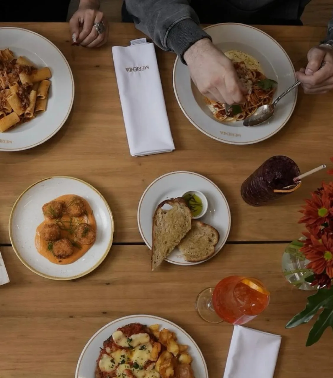 Mesa servida en Merienda vista desde arriba con pastas, milanesa napolitana, croquetas y tragos
